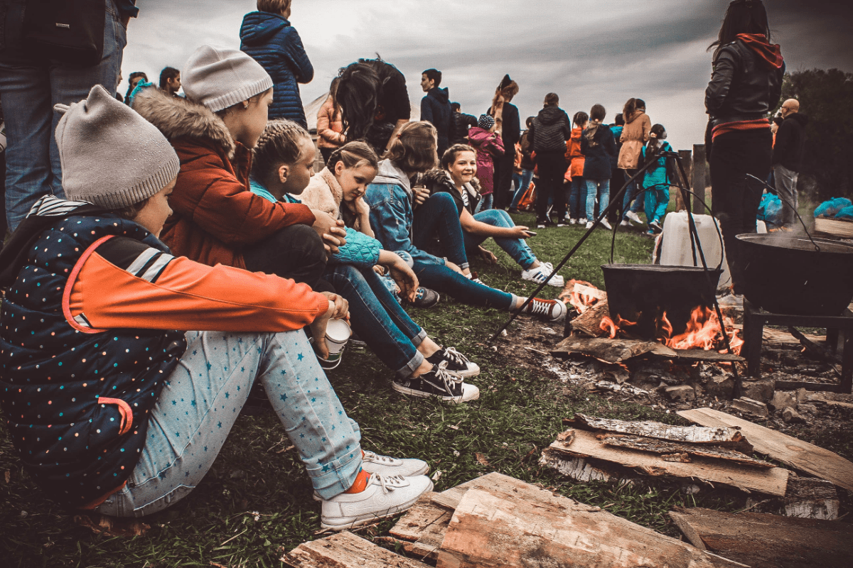 A group of children sitting next to a campfire